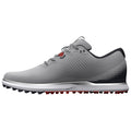 A gray golf shoe with a sleek design features a textured surface and perforated details while standing still on a white background showcasing its low-profile silhouette and spiked outsole for traction.