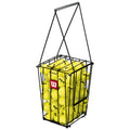 A black wire basket holds multiple yellow tennis balls with the Wilson logo visible on them. The basket has a handle for easy transport, designed for carrying tennis equipment.