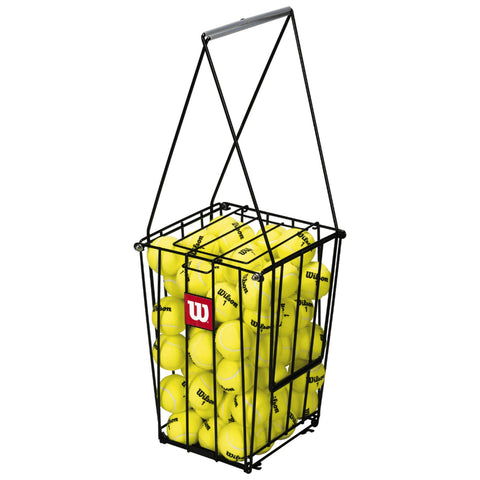 A black wire basket holds multiple yellow tennis balls with the Wilson logo visible on them. The basket has a handle for easy transport, designed for carrying tennis equipment.