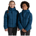 Two children are smiling while wearing matching blue puffy jackets with hoods. They stand close together in a neutral white background, exuding warmth and friendliness.