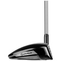 A golf driver with a sleek black and silver design featuring the brand name TaylorMade on the front stands upright against a plain background ready for use on the golf course.