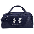 A large navy duffel bag with a prominent white Under Armour logo sits motionless, featuring dual handles and a removable shoulder strap, suitable for athletic gear and travel.