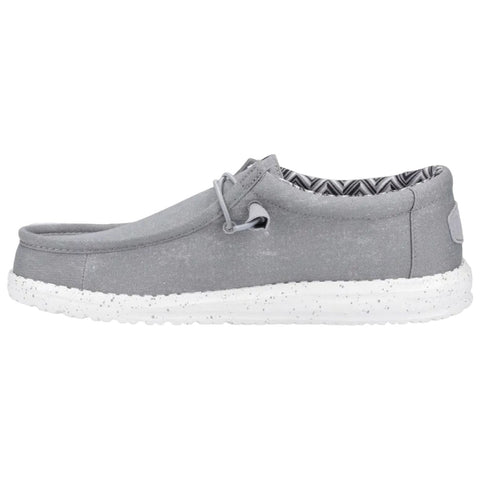 A gray slip-on shoe with a soft fabric upper features a white speckled sole and a patterned interior lining designed for casual wear resting on a plain background.