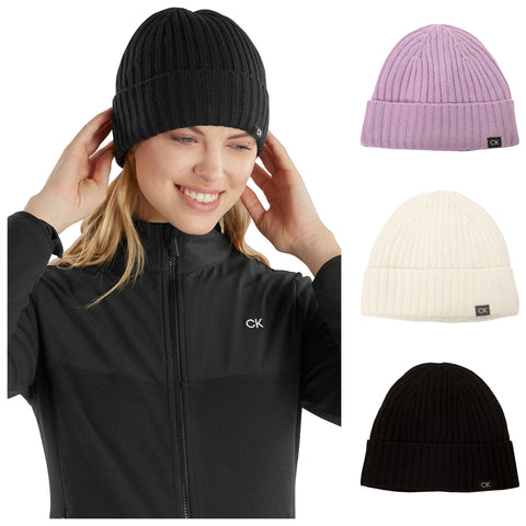 A woman wears a black ribbed knit beanie while smiling and adjusting it. Surrounding her are additional beanies in lavender, white, and black displayed beside her.