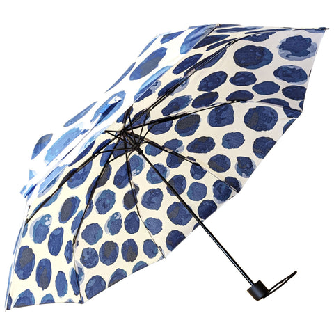 A blue and white polka-dotted umbrella is opened above with a black handle visible below against a light background creating a playful and vibrant appearance.