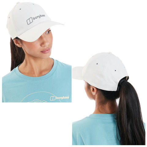 A white cap rests on a young woman's head as she turns towards her left side showing long dark hair tied back and wearing a blue shirt with a graphic design.