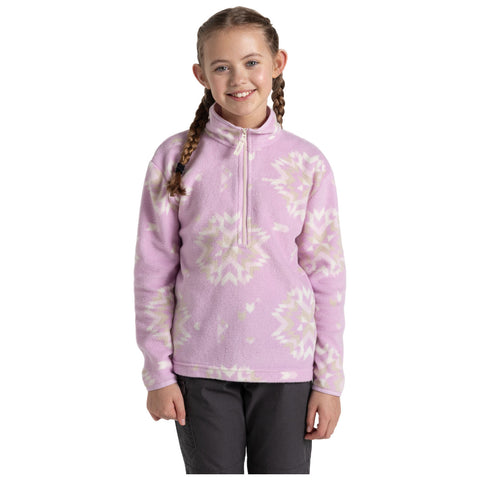 A young girl stands smiling in a cozy pink fleece pullover with a zippered neck. She has two braids and is wearing dark pants, against a plain white background.