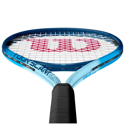 A tennis racket is prominently displayed with a blue frame and black grip showcasing a white string bed featuring a large red logo in the center against a plain background.