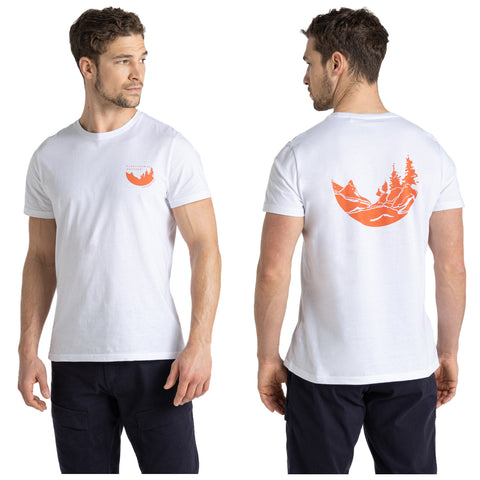 A man in a white t-shirt stands facing slightly to the side showcasing a graphic of trees and mountains printed in orange on the back and a small logo on the front.