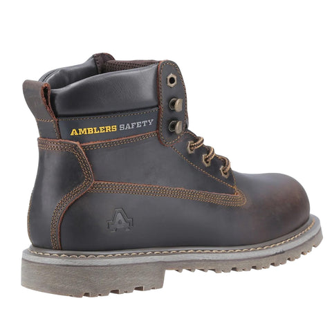 A black safety boot is displayed upright showing its sturdy leather material and brown accents. Laces are tied and it features a textured sole for traction on various surfaces. AMBLERS SAFETY is visible on the upper side.