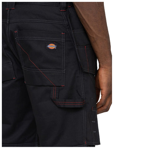 Black cargo shorts are worn by a person showing their back with visible pockets and red stitching highlighted against the fabric in an outdoor or casual environment.