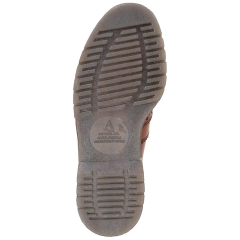 A brown shoe sole with textured grooves is shown resting on a flat surface conveying stability designed for grip and featuring labeling indicating petrol oil and acid alkali resistance.