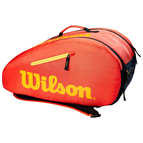 A red and black sports bag features the Wilson logo prominently in yellow. The bag is zipped and has a handle, designed for carrying sports equipment or gear.