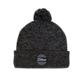 A dark knitted beanie is displayed with a pom-pom on top and a circular logo patch reading "Titleist" on the front, suitable for cool weather wear.