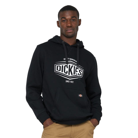 A person stands confidently wearing a black hoodie featuring a prominent logo that reads DICKIES with a kangaroo pocket and relaxed posture set against a white background.