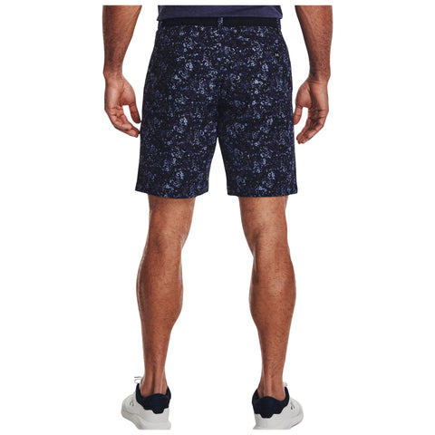 A person stands facing away, wearing navy floral shorts and white athletic shoes, in a casual setting, highlighting the shorts' intricate design and relaxed fit.