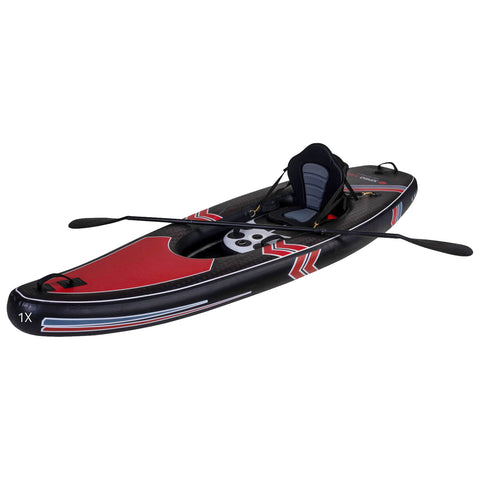 A red and black kayak is positioned on a flat surface with a padded seat and two paddles resting beside it, suggesting preparation for water-based activities in an outdoor environment.