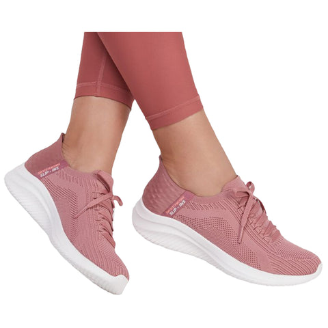 Pink athletic shoes are worn on feet with laces tied while legs are partially visible. The setting likely suggests a casual or active environment such as a gym or outdoors.