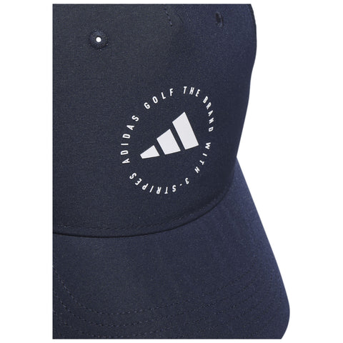 A navy blue cap features a circular logo with three stripes and text stating "ADIDAS GOLF THE BRAND WITH 3 STRIPES" on the front, displayed against a smooth fabric background.