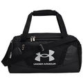 A black duffel bag features dual carrying handles and a removable shoulder strap while displaying a prominent silver Under Armour logo on the side, set against a neutral background.