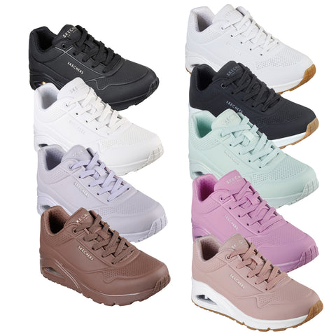 Multiple pairs of Skechers sneakers in various colors including black white mint green lavender brown and pink are displayed standing upright showcasing their design and materials against a plain background