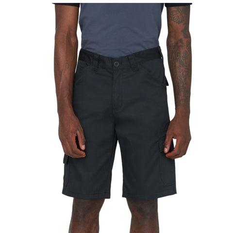 A person stands wearing black cargo shorts with pockets and a gray shirt their arms are crossed and display tattoos the background is plain white