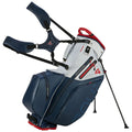 A golf bag stands upright featuring a waterproof design with multiple zippered compartments and adjustable straps for carrying. It has sturdy legs extending for support on the ground.