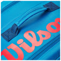 A blue bag with a textured surface features a prominent red word "Wilson" printed on it and a sturdy blue handle for carrying or transport.