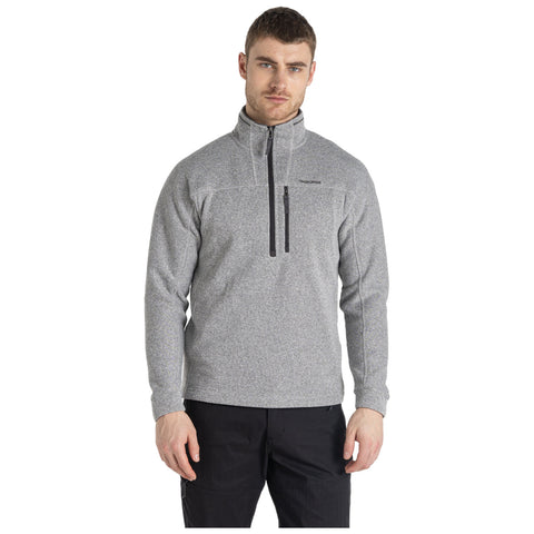 A man stands confidently wearing a light gray fleece pullover with a half zip and black accents in a neutral setting, showcasing a casual yet stylish outdoor look.