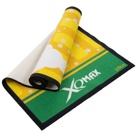 A brightly colored bar mat features a yellow beer design with bubbles and a green side displaying the text XQMAX and the measurement 23x27cm while partially rolled up.