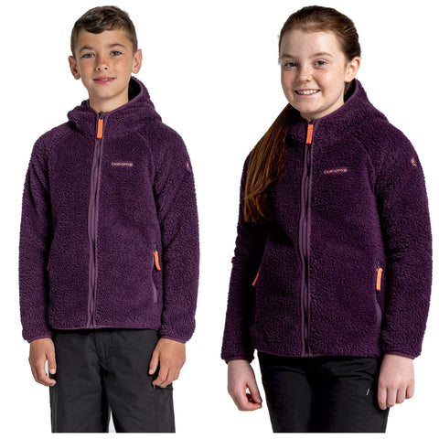 Two children are wearing purple fleece jackets with zip fastenings and orange accents they are standing upright against a neutral background smiling at the camera.