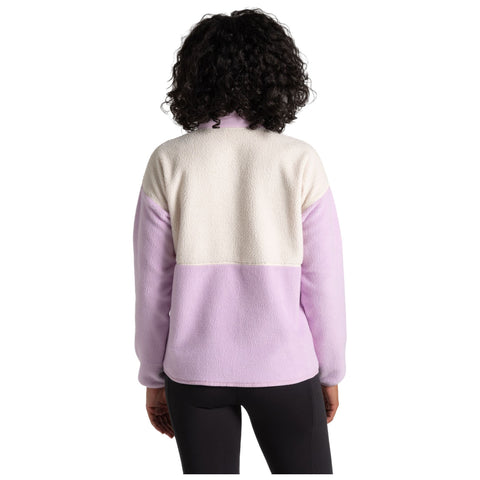 A person is wearing a cozy fleece jacket featuring a color-block design with lavender and cream colors. The setting appears casual and relaxed with no specific background details visible.