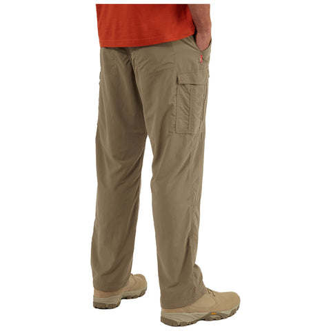 Khaki cargo pants are worn by a person standing still with hands in side pockets on a simple background. The pants feature side cargo pockets and are paired with light footwear.