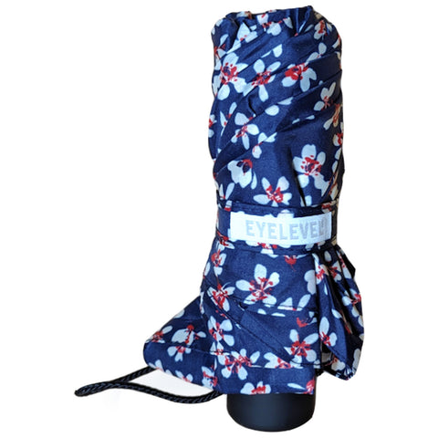 A compact, folded umbrella covered in a navy floral pattern sits upright with its handle visible, designed for protection against rain while being easily portable.