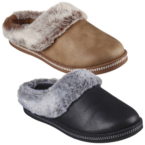 Two pairs of slippers are displayed side by side one is tan with a brown fur lining and the other is black with a gray fur lining both have closed backs and soft textures