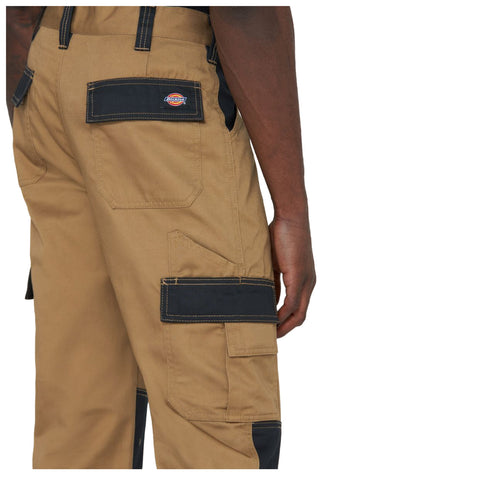 Tan cargo pants are worn by a person with a hand resting on the side. The pants feature multiple pockets and black accents, suitable for work or casual wear.