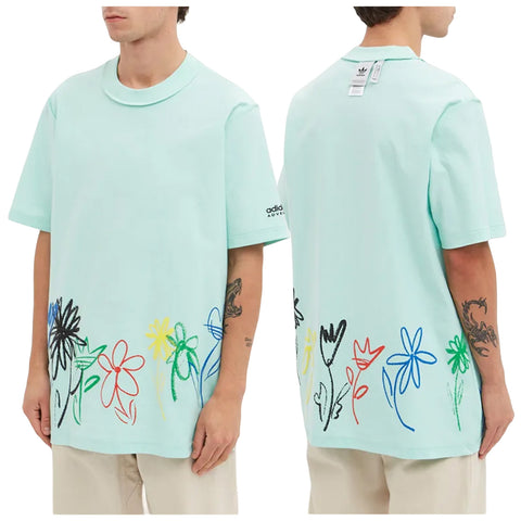 A mint green short-sleeved t-shirt features colorful floral embroidery along the bottom hem and an Adidas logo on the sleeve while the model stands against a plain background.