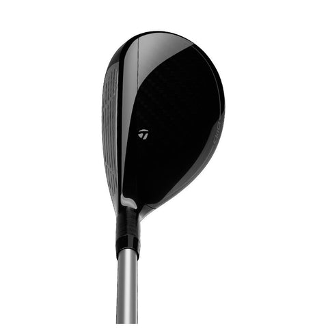 A black golf club head is positioned upward showcasing a glossy finish and structured face designed for striking a golf ball in an outdoor playing environment like a golf course.