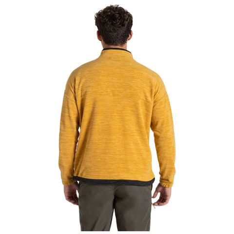 A person wearing a yellow pullover shirt stands with their back facing the viewer in a neutral outdoor setting, showcasing a casual style suitable for cooler weather.