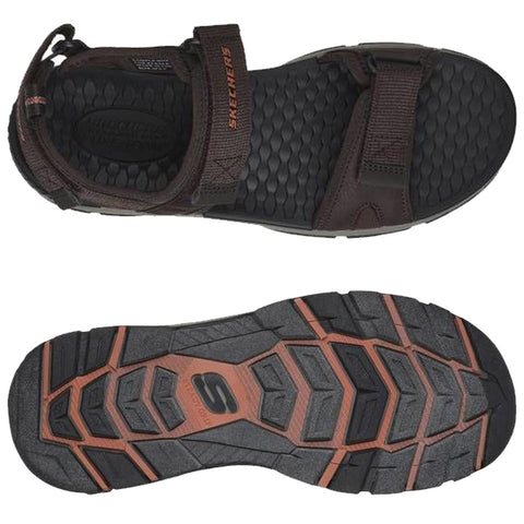 A brown sandal is displayed from an overhead view featuring adjustable straps and a textured sole with a prominent logo designed for comfort and traction in outdoor settings.