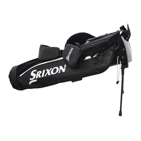 A black golf bag with the Srixon logo is standing upright with a retractable support leg extended the bag has multiple compartments and padded straps for carrying.