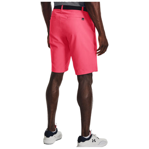 A person is standing with their back turned, wearing bright pink shorts and athletic shoes, in a casual setting, showcasing a sporty outfit and muscular legs.