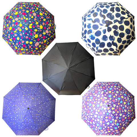 Five umbrellas are displayed with various designs including colorful fruits polka dots hearts and a solid black one arranged in an open position against a plain background.