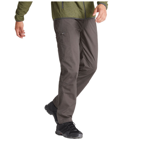 A person walks in comfortable outdoor clothing featuring green and brown pants paired with black hiking shoes in a casual setting suggesting an active outdoor environment.