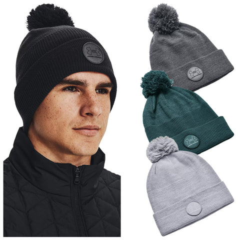 Three individuals wear different colored knit beanies with pom-poms. Each hat features a logo. The men are dressed in athletic outerwear, suggesting a casual or sporty outdoor setting.