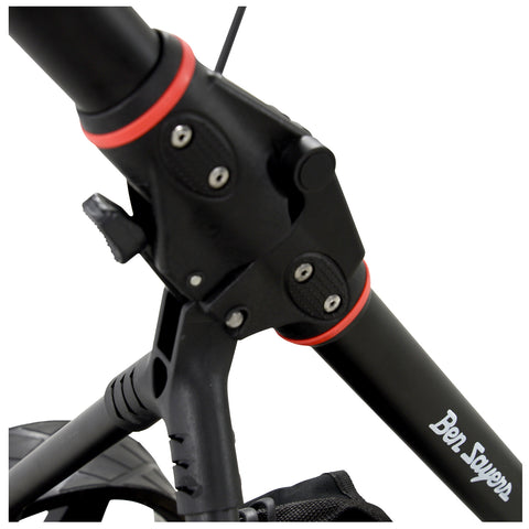 A black and red handlebar of a scooter features adjustment mechanisms attached to a pole surrounded by a textured mount and a black bag at the base on a surface.