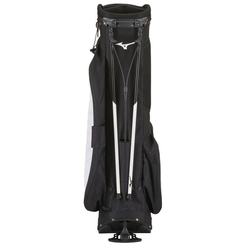 A black and white golf bag stands upright showcasing its zipped top compartment and two white support poles extending from the base in a neutral background.