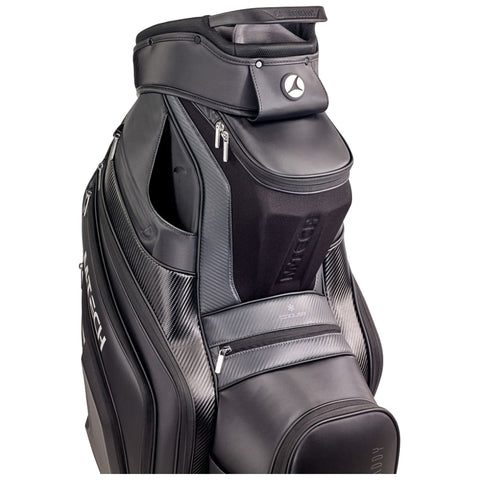 A black golf bag stands upright featuring multiple zippered compartments and a sleek design that combines leather and fabric elements with branding prominently displayed on the side.