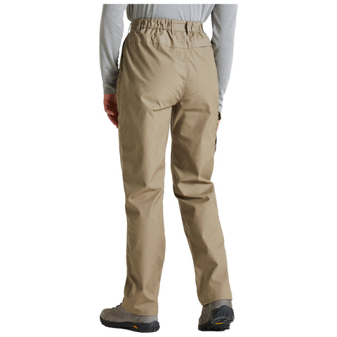 A person is wearing light beige hiking pants with an elastic waistband and is facing away from the viewer in a casual outdoor setting with gray long-sleeve shirt and sturdy footwear.