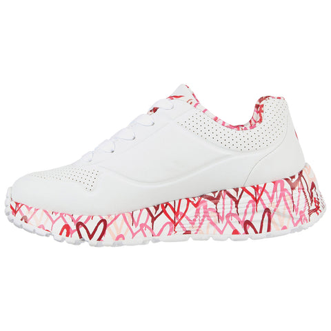 A white sneaker with a textured sole featuring a colorful heart design is positioned to display its side profile emphasizing the unique base and lace-up design.